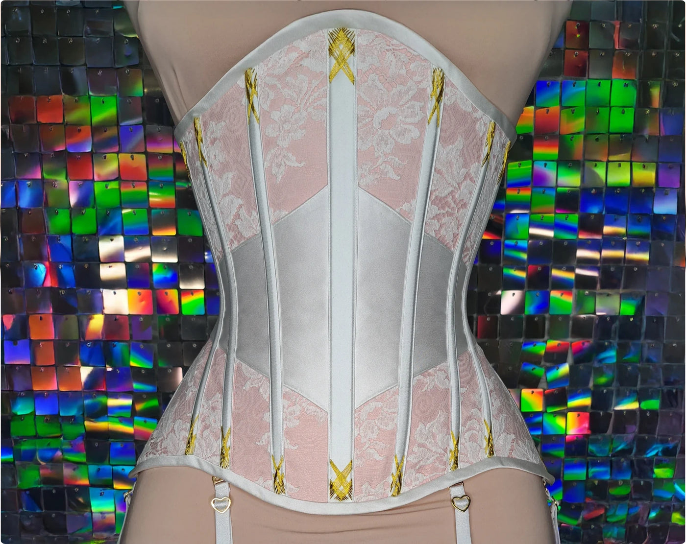 Pink dupioni satin underbust corset with solid front, butterfly lacing, white contrasting accents, flossing embroidery in golden thread and lace overlay — the finished corset
